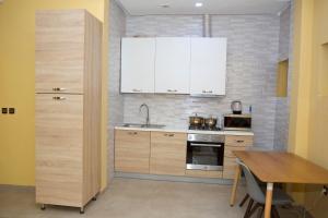 une cuisine avec des armoires blanches et une table en bois dans l'établissement StayAfrica, à Ouagadougou