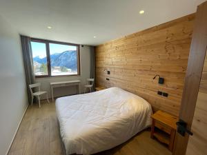 une chambre avec un lit et un mur en bois dans l'établissement Les Sorbiers Appartements, à Montricher-Albanne 23 autres photos