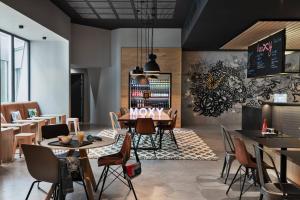 サン・テグジュペリにあるMoxy Lyon Airportのテーブルと椅子のある壁のレストランで、