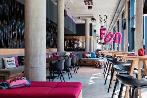 ein Restaurant mit Tischen und Stühlen und einer roten Couch in der Unterkunft MOXY Vienna Airport in Schwechat