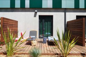 a patio with two chairs and plants in front of a building at Moxy Antibes Sophia Antipolis in Biot