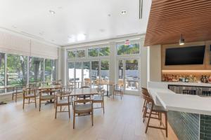 a dining room with tables and chairs and windows at Hilton Garden Inn LAX - El Segundo in El Segundo