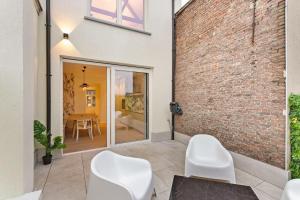una stanza con due sedie bianche e un muro di mattoni di Luxe Stay in Heart of Mechelen a Mechelen