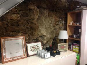 a stone wall with a table with a lamp and pictures at Quinta dos Castanheiros - Turismo Rural in Negreda