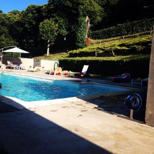 a swimming pool with chairs and umbrellas next to at Quinta dos Castanheiros - Turismo Rural in Negreda