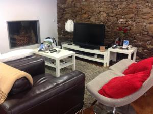 a living room with a couch and a tv at Quinta dos Castanheiros - Turismo Rural in Negreda