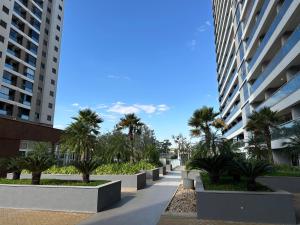 a walkway between two tall buildings with palm trees at Studio Duo Jk White in Sao Jose do Rio Preto