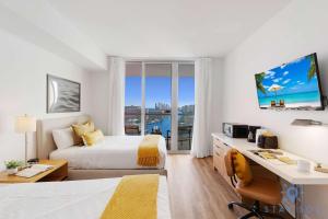 a hotel room with a bed and a desk and a window at Amazing Studio Near the Beach in Hallandale Beach