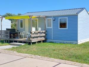 a blue tiny house with a porch and a deck at Chalet Goudrenette in Hengstdijk