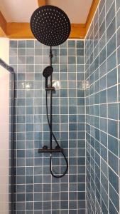 a shower with a shower head in a blue tiled bathroom at Jolie maison landaise proche de la plage in Messanges