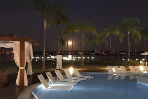 a group of white chairs next to a pool at night at Brisas do Lago - apt 13 in Brasilia