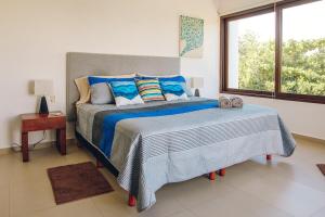 a bedroom with a large bed with blue sheets and a window at Serene Jungle Villa -Steps from the Ocean in Akumal
