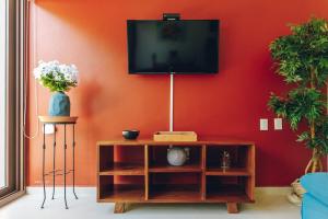 a living room with a tv on a red wall at Serene Jungle Villa -Steps from the Ocean in Akumal