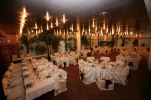 uma sala cheia de mesas com lençóis brancos e lustres em Hotel Lovech em Lovech