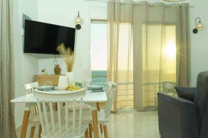 a living room with a table and chairs and a television at Cocoscape Seaside Suite, With Sea View in Kalamaki Heraklion