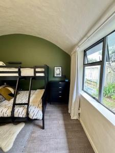 a bedroom with bunk beds in a room with a window at Iconic & Curvaceous Beach House in Waikanae +39 photos