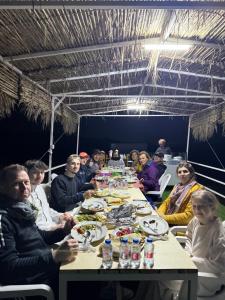 a group of people sitting at a table eating food at Royal desert camp in Al Raka