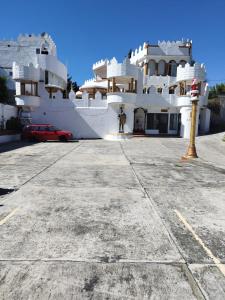 a large white building with a red car parked in front at Castillo del Rey in Valle de Bravo