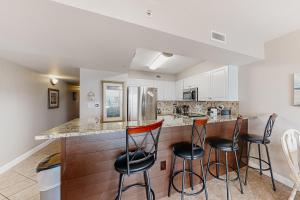a kitchen with a bar with three stools at Pelican Isle 204 Gulf Clap in Fort Walton Beach
