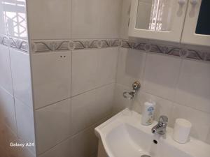 Un baño blanco con lavabo y espejo. en De Serene B&B, en Midrand