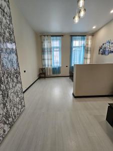an empty room with a table and two windows at Homy in Gyumri