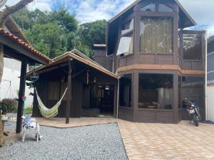 a house with a hammock and a motorcycle parked outside at Quarto ECONÔMICO - Suíte in Camboriú