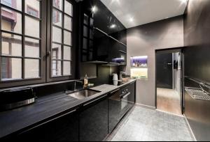 a black kitchen with a sink and a refrigerator at La Cachette St Jean, Calme et Sérénité Vieux Lyon in Lyon
