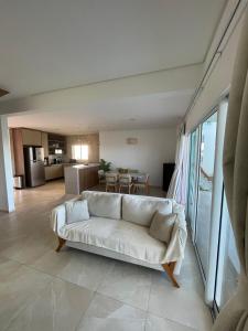 a living room with a white couch and a kitchen at Casa Beira Mar com Piscina Maragogi - Amar & Mar in Maragogi