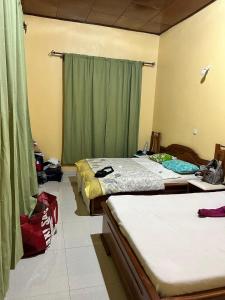 ein Schlafzimmer mit zwei Betten und einem Fenster in der Unterkunft Villa Serena in Bandjoun