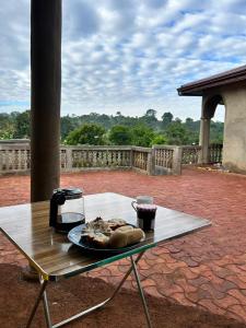 einen Tisch mit einem Teller Essen und einem Drink darauf in der Unterkunft Villa Serena in Bandjoun
