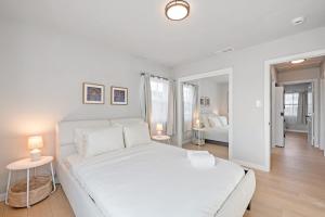 a white bedroom with a large bed and two lamps at Luxury Modern Retreat with Spacious Yard & Premium Comfort in Monrovia
