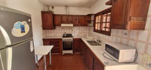 Una cocina con gabinetes de madera y microondas. en Casa Ostende Junin, en Ostende