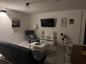a living room with a couch and a tv on the wall at Ferienwohnung Erzgebirgsglück OG in Jöhstadt