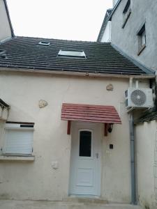 a white house with a door and a fan at petite maison cosy in Auneau