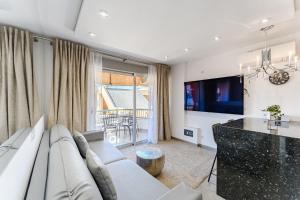 Una sala de estar con un sofá blanco y un televisor. en Hermitage Homes TDS, en Playa de las Américas