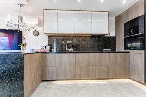 una cocina con encimeras de granito negro y armarios blancos en Hermitage Homes TDS, en Playa de las Américas