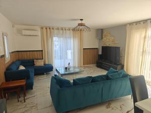 a living room with a blue couch and a tv at Villa luxe 5 chambres piscine jacuzzi homegym in Castelnau-le-Lez +50 photos