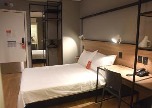 a bedroom with a bed and a desk with a phone at ibis Tangará Da Serra in Tangara da Serra +174 photos