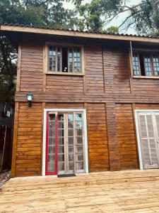 a log cabin with a red door and two windows at Ilha do Mel- Encantadas- Vilarejo Hospedagem in Ilha do Mel