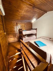 a room with three beds in a wooden cabin at Vilarejo Hospedagem - Encantadas in Ilha do Mel