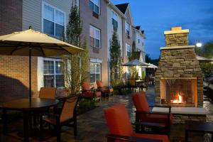 un patio con mesas y sillas y una chimenea de piedra. en TownePlace Suites by Marriott East Lansing, en East Lansing