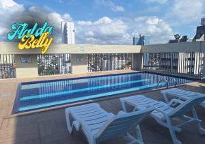 a swimming pool with two chairs next to a building at Flat da Belly 904-A Hidro Piscina Praia in São Vicente
