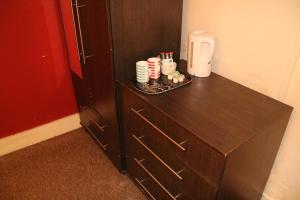 a brown cabinet with a tray of cups on it at London Olympus Hotel Nirvana in London