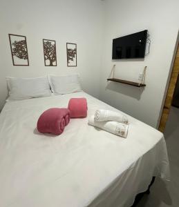 a white bed with two pink pillows on it at Casa 02 na villa uryah in Caraíva