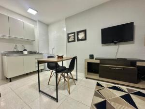 a kitchen with a table and a tv on the wall at Studio no coracao do Kobrasol in São José