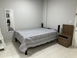 a bedroom with a bed and a dresser and a mirror at Studio no coracao do Kobrasol in São José