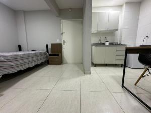 a room with a kitchen and a bed and a table at Studio no coracao do Kobrasol in São José