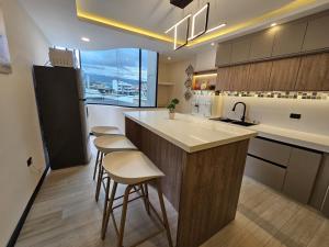 a kitchen with a sink and a counter with stools at Departamentos SKYHOME 202 in Cuenca