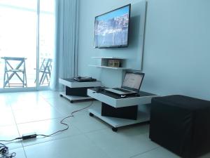 um quarto com um computador portátil numa mesa com uma televisão em Apartamento Hélio Gregório Barra da Tijuca no Rio de Janeiro