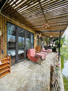 a covered patio with a bed and chairs on it at Wild Orchid Relaxing Bungalow in Làng Cac